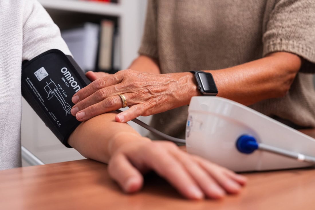 Domowy pomiar ciśnienia krwi za pomocą cyfrowego ciśnieniomierza i lekarza lub opiekuna.