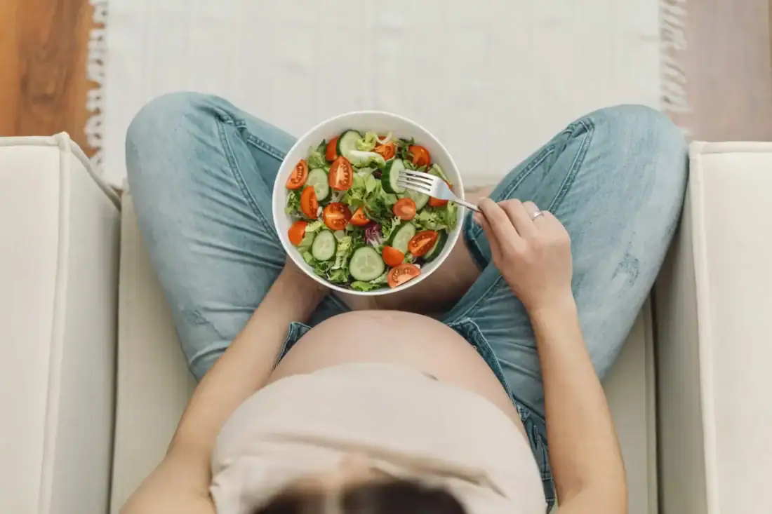 Zdrowa sałatka z warzywami i pomidorami, kobieta je pożywną i zbilansowaną dietę.